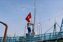 Fishermen raise the national flag before heading out to the sea to affirm Vietnam’s sovereignty over its seas and islands. (Photo: VNA)