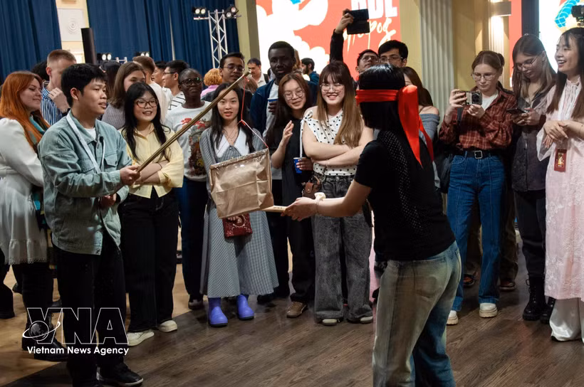 Young participants from India, Indonesia and Russia learn about the traditional pot-breaking game. (Photo: VNA)