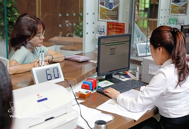 A customer conducts a transaction at a Vietcombank office in Hanoi. (Photo: VNA)