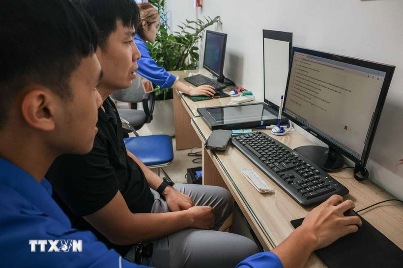 Youth union volunteers assist local residents in filing online birth certificate applications for their children at the Cua Nam ward public service centre. (Photo: VNA)