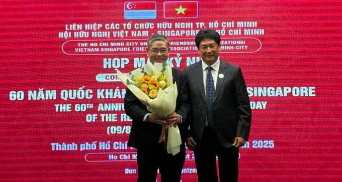 Chairman of the Vietnam–Singapore Friendship Association of Ho Chi Minh City Lam Dung Tien presents flowers to Singapore Consul General in HCM City Pang Te Cheng at the gathering. (Photo: sggp.org.vn)