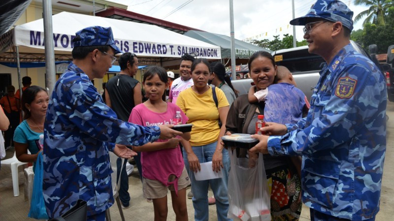 An officer of the Vietnam Coast Guard delegation presents meal portions to residents affected by the earthquake in Bogo province, the Philippines. (Photo: nhandan.vn)