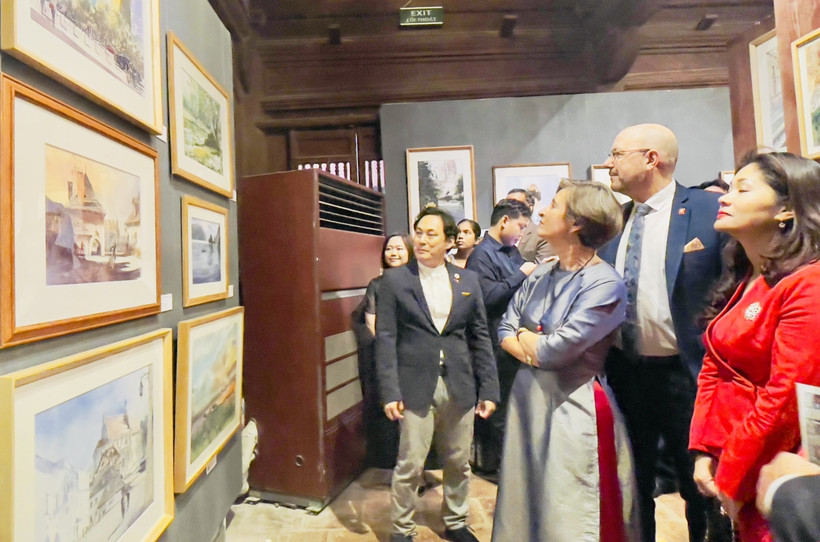 Painter Minh Dam introduces the exhibited works to visitors at the exhibition. (Photo: VNA)