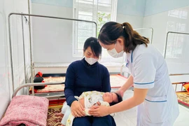 A kid receives health checkup after vaccination. (Photo: VNA)