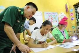 Lieutenant Lo Thanh Chuyen of the Leng Su Sin Border Guard Station assists teachers in a class in Ca Na Pa village in Diện Bien province. (Photo: VNA)