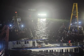 At 2:00 a.m. on July 20, rescue teams begin pumping water out of the capsized tourist boat before towing it ashore. (Photo: VNA)