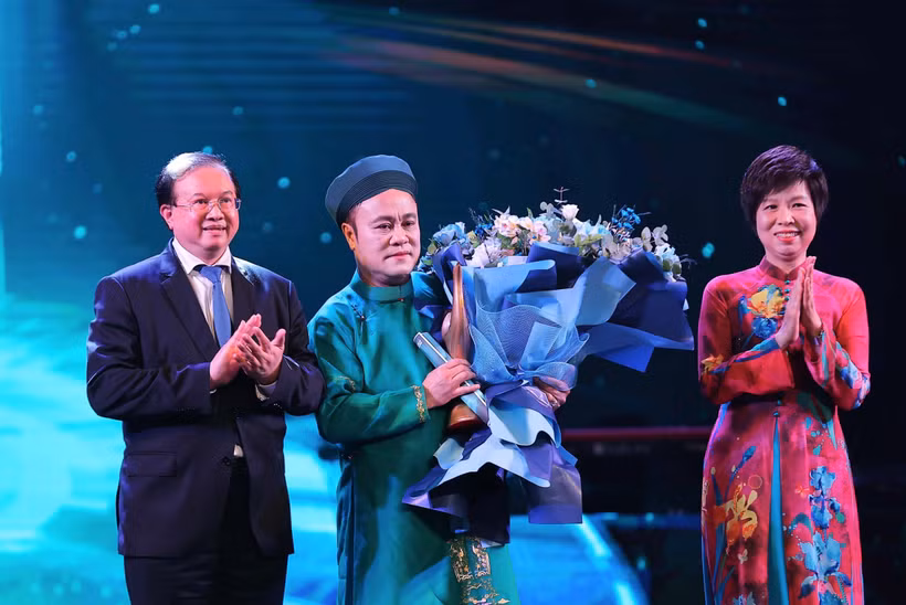 Vietnam News Agency General Director Vu Viet Trang (R) and Deputy Minister of Culture, Sports and Tourism Ta Quang Dong (L) present the "Inspiring Artist" Award to artist Chu Bao Que. (Photo: VNA)