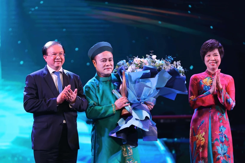 Vietnam News Agency General Director Vu Viet Trang (R) and Deputy Minister of Culture, Sports and Tourism Ta Quang Dong (L) present the "Inspiring Artist" Award to artist Chu Bao Que. (Photo: VNA)