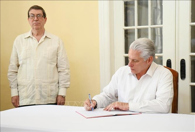 First Secretary of the Communist Party of Cuba Central Committee and President of Cuba Miguel Diaz-Canel Bermudez writes in the condolence book. (Photo: VNA)