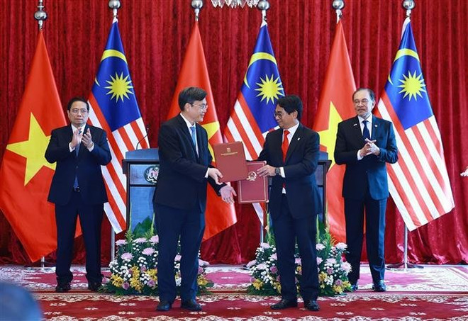 Vietnamese Prime Minister Pham Minh Chinh (L) and his Malaysian counterpart Anwar Ibrahim witness the exchange of a letter of intent on cooperation between the Vietnam National University, HCM City and the National University of Malaysia. (Photo: VNA)