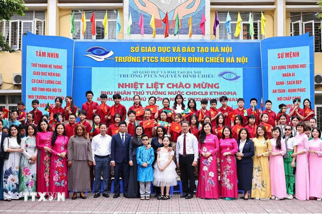 The spouses of the Vietnamese and Ethiopian PMs pose for a group photo with teachers and students of the Nguyen Dinh Chieu secondary school. (Photo: VNA) nguyen-dinh-chieu-secondary-school.jpg