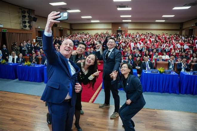 New Zealand Prime Minister Christopher Luxon takes a photo with FTU lecturers and students at the event. (Photo: VNA) vna-potal-thu-tuong-new-zealand-christopher-luxon-giao-luu-voi-sinh-vien-dai-hoc-ngoai-thuong-ha-noi-7875412.jpg