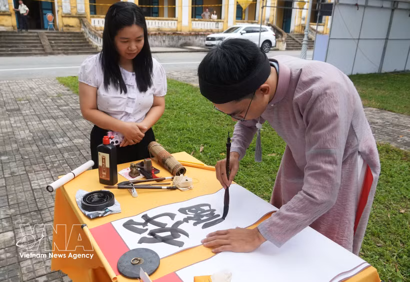 A visitor watches a calligraphy demonstration at the first Vietnam Calligraphy Festival 2026. (Photo: VNA)