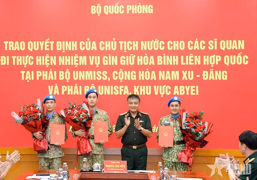 Senior Lieutenant General Nguyen Van Hien presents the President’s decisions to three officers assigned to UN peacekeeping missions. (Photo: qdnd.vn)