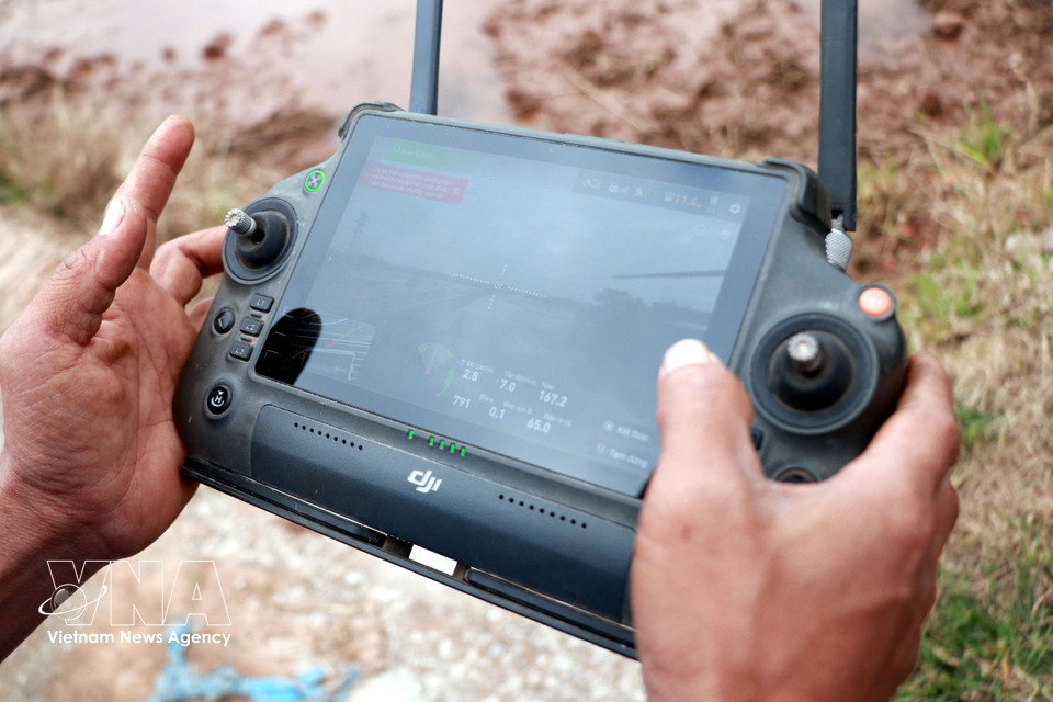 A member of the Nam Dai Duong Youth Cooperative in Nghia Hung commune, Ninh Binh province operates an unmanned aerial vehicle to sow rice. (Photo: Nguyen Lanh – VNA)