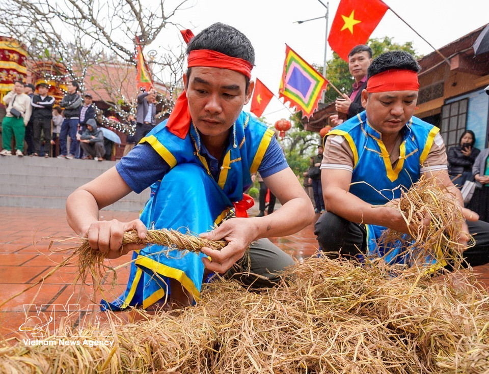 Team members braid straw into long bundles to use as fuel and cushioning for the stone mortars, a stage requiring skill to keep the fire burning evenly and steadily. (Photo: Khanh Hoa – VNA)