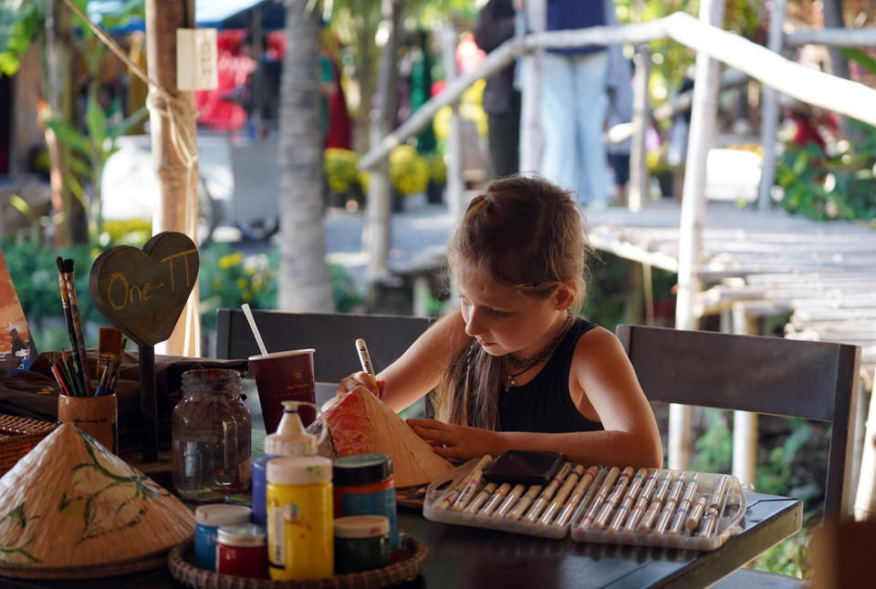 A foreign child tries her hand at traditional calligraphy at the Old Tet space. (Photo: Dang Tuan – VNA)