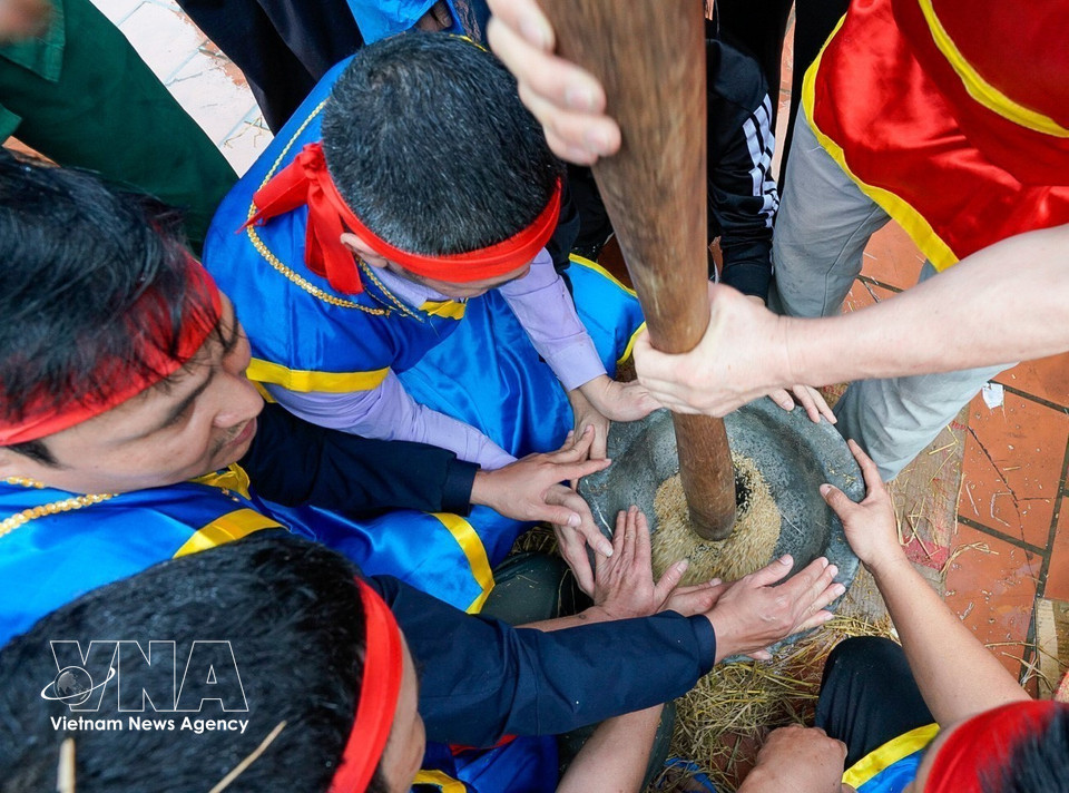 Young men pound unhusked rice in a stone mortar. (Photo: Khanh Hoa – VNA)