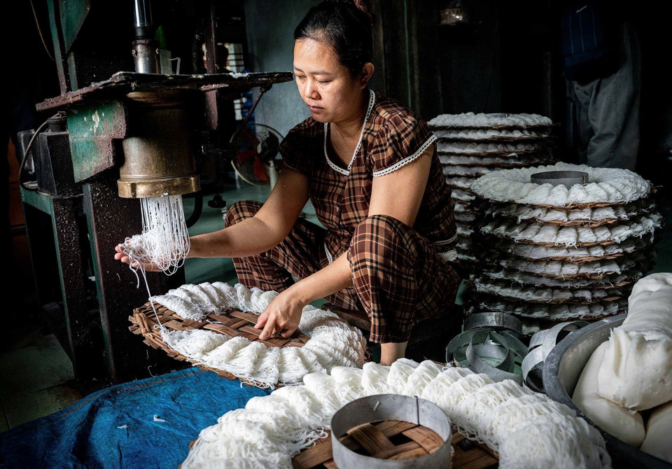 As the dough is pressed through the extruder, it emerges in fine strands. The artisan swiftly catches and separates them by hand into small, even portions, neatly arranged on bamboo trays. (Photo: Khanh Hoa - VNA)