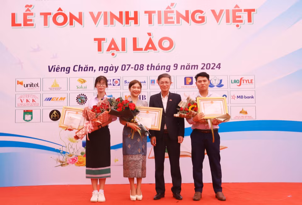 Chargé d'Affaires of the Vietnamese Embassy in Laos Phan Minh Chien presents certificates and awards to three contestants participating in the final round of the "Vietnamese Language Ambassador Abroad 2024" competition. (Photo: VNA)