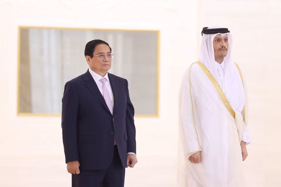 Prime Minister Pham Minh Chinh and Qatari Prime Minister Sheikh Mohammed bin Abdulrahman bin Jasim Al-Thani listen to the national anthems of both nations played by a military band. (Photo: Duong Giang-VNA)