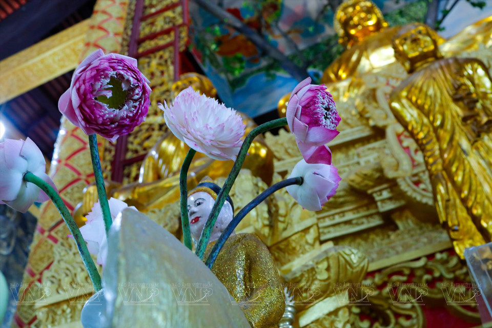 People offer flowers to the Buddha during the prayer ceremony. (Photo: VNA)