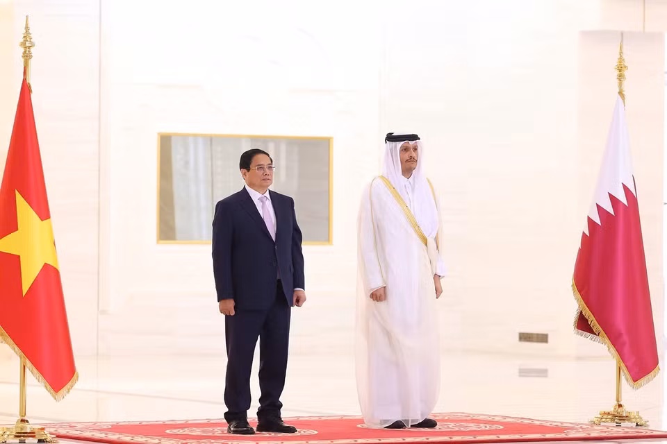 Prime Minister Pham Minh Chinh and Qatari Prime Minister Sheikh Mohammed bin Abdulrahman bin Jasim Al-Thani listen as the military band plays the national anthems of both countries. (Photo: Duong Giang-VNA)