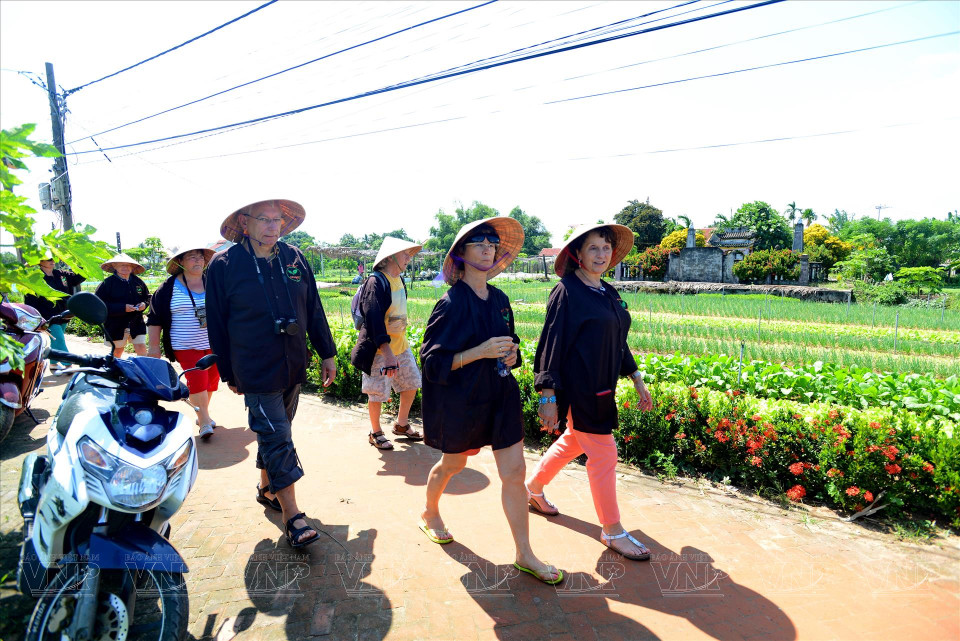 Foreign tourists take a tour of the village. (Photo: Thanh Hoa/VNA)