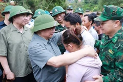 Prime Minister Pham Minh Chinh consoles a family whose member dies in recent floods in Xa Dung commune. (Photo: VNA)