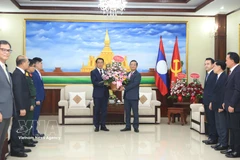 Ambassador Nguyen Minh Tam presents Party General Secretary To Lam's flowers to the LPRP Central Committee's External Relations Commission to congratulate on the LPRP's 71st founding anniversary. (Photo: VNA) 