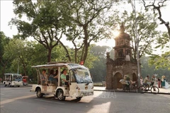 Tourists travel around Hoan Kiem Lake by electric cars. (Photo: VNA)