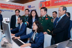 General Nguyen Trong Nghia (standing, front, second from right) visits Vietnam News Agency reporters covering the 14th National Party Congress on January 20. (Photo: VNA)