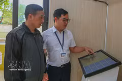 A civil servant at the Van Thang commune Public Administrative Service Centre in Ninh Binh province guides a resident on how to obtain a queue number using the machine. (Photo: VNA) 
