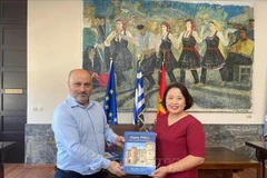 Deputy Mayor of Rhodes in charge of economy, finance, and cultural heritage Chalkias Konstantinos (L) presents a book to Vietnamese Ambassador to Greece Pham Thi Thu Huong. (Photo: Published by VNA)