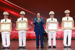 Prime Minister Pham Minh Chinh (middle) presents the Hero of the People’s Armed Forces title to outstanding individuals and collectives of the the People’s Public Security force. (Photo: VNA)