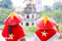 Visitors wearing national flag-themed conical hats at Hoan Kiem Lake, an icon of Hanoi (Photo: VNA)