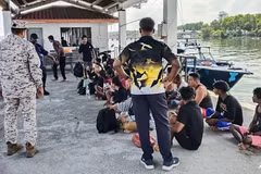 A Malaysian Maritime Enforcement Agency staff member checks on survivors rescued during a search and rescue operation off the coast of Pangkor Island in Perak on May 12, 2026, after a boat carrying migrants capsized. (Photo: AFP/Malaysian Maritime Enforcement Agency)