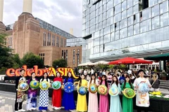 The Vietnamese delegation parades in traditional ao dai and conical hats along the streets of London. (Photo published by VNA) 