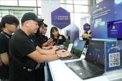 Visitors to a booth introducing technology products at the Vietnam Blockchain Summit 2022. (Illustrative photo: VNA)