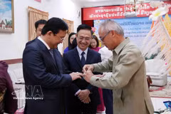 Phonesy Bounmixay (right), Lao Consul General in Ho Chi Minh City, performs the traditional baci string-tying ceremony to offer New Year blessings to a member of the Ho Chi Minh City delegation on April 10, 2026. (Photo: VNA)