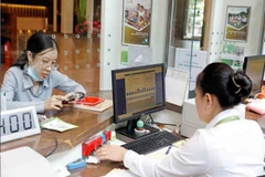 A customer conducts a transaction at a Vietcombank office in Hanoi. (Photo: VNA) 