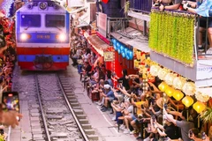 Tourists pose for photos at 'train street' on March 22, 2025. (Photo: VNA)