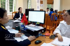 A Phu Tho civil servant guides a local how to switch from presumptive tax mechanism to tax sef-declaration. (Photo: VNA)