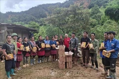 A representative of the Dien Bien Red Cross Society presents relief supplies to local residents. (Photo: VNA)
