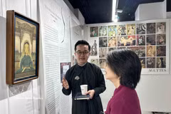 Artist Lam Gia Huan introduces his winning piece to a visitor. (Photo: VNA)