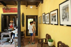 Tourists view photos exhibited in the heritage house on 87 Ma May street, Hanoi. (Photo: VNA) 