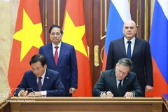 Vietnamese PM Pham Minh Chinh (standing, left) and his Russian counterpart Mikhail Mishustin (standing, right) witness the signing of the agreement between the two governments on cooperation in building a nuclear power plant on the territory of Vietnam. (Photo: VNA)