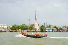 Narrow wooden boats laden with produce cross the Mekong with Cai Be church in the background. (Photo: The Sydney Morning Herald)