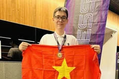 Le Tuan Minh holds the national flag to celebrate his win in rapid chess event of the Asian Mind Sports Conference & Festival which closed on November 15 in Singapore. (Photo: VNA)