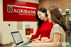 An Agribank staff instructs a customer to conduct safe digital transactions (Photo: qdnd.vn)